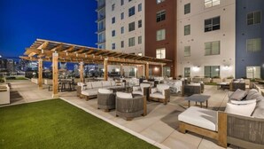 An outdoor patio area with multiple seating arrangements, including sofas and chairs, under a wooden pergola. - Midnight Manor Penthouse Suite The Gulch (Nashville)