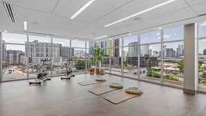 A spacious gym with large windows, exercise equipment, and a city view. - Midnight Manor Penthouse Suite The Gulch (Nashville)