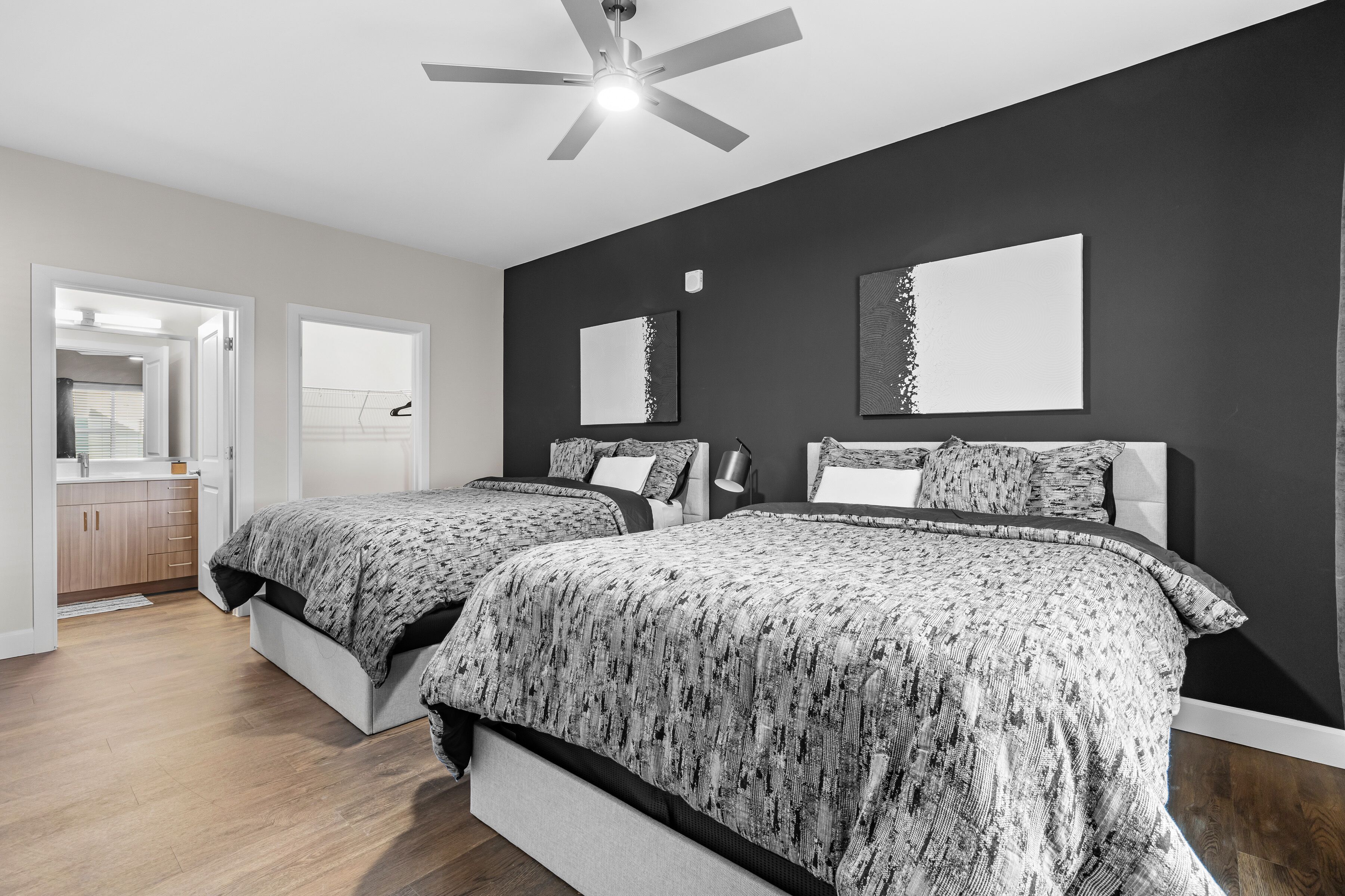 A bedroom with two beds, a ceiling fan, and a view of the hallway.