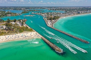 An aerial view of a coastal area with a beach, a pier, and boats.