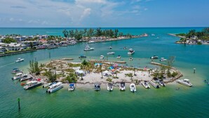 Un port de plaisance avec des bateaux amarrés, une plage de sable et un ciel bleu dégagé.