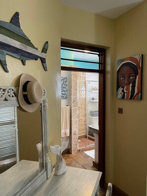 Relax in a stylish room with a large mirror, wooden floor, and a bathroom featuring a glass shower enclosure.