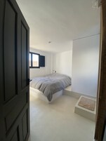 Un dormitorio con cama, ventana y puerta.
