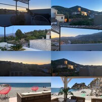 Un hotel con terraza que cuenta con sillas de mimbre, vistas a un pueblo en la ladera y una playa con sombrillas.