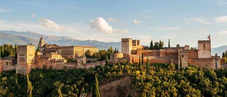 A historic fortified city with medieval architecture, including towers and a large building with a prominent tower.
