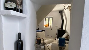 Un passadís estret amb parets blanques, un arca de fusta i dues ampolles de vi sobre una prestatgeria.