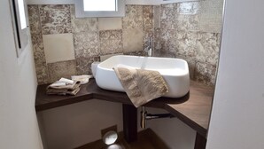 Un bany amb sostre de fusta, una finestra, un lavabo i un mirall.