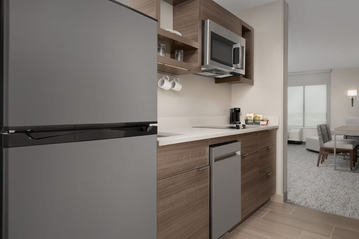 A modern kitchen with a built-in microwave, a dishwasher, and a countertop with a coffee maker and jars.