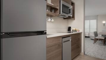 A modern kitchen with a built-in microwave, a dishwasher, and a countertop with a coffee maker and jars.