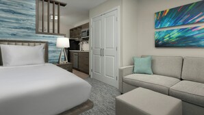 A hotel room with a bed, a sofa, a desk with a lamp, a microwave, and a kitchen area. - TownePlace Suites by Marriott Abilene Southwest (Abilene)