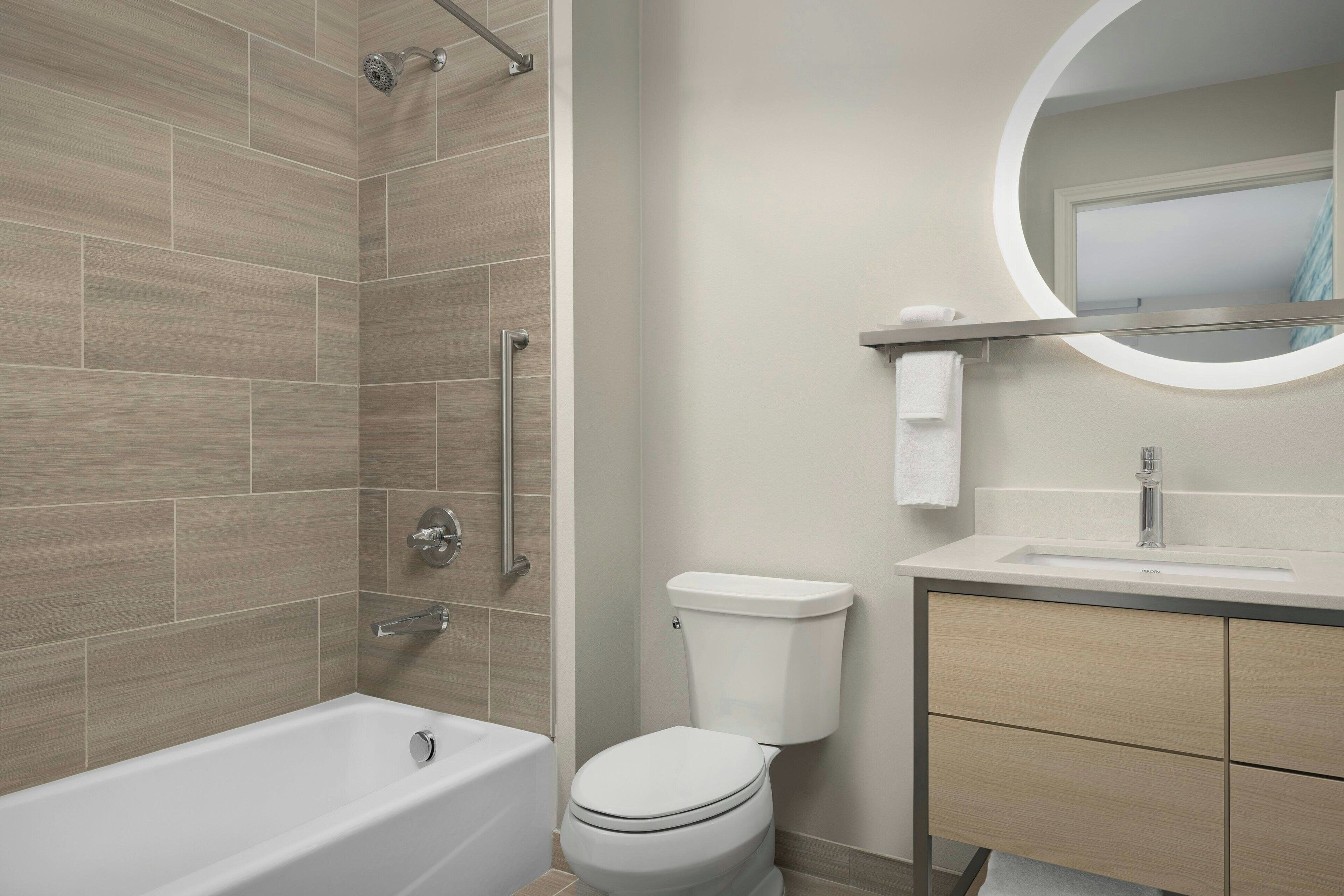 A modern bathroom with a bathtub, toilet, and vanity.