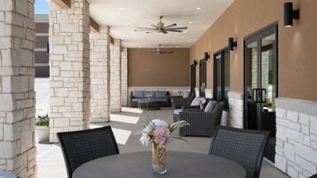 An outdoor patio area with a round table, chairs, a sofa, and a ceiling fan.