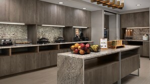 A modern kitchen with granite countertops, wooden cabinets, and a central island with fruit baskets. - TownePlace Suites by Marriott Abilene Southwest (Abilene)