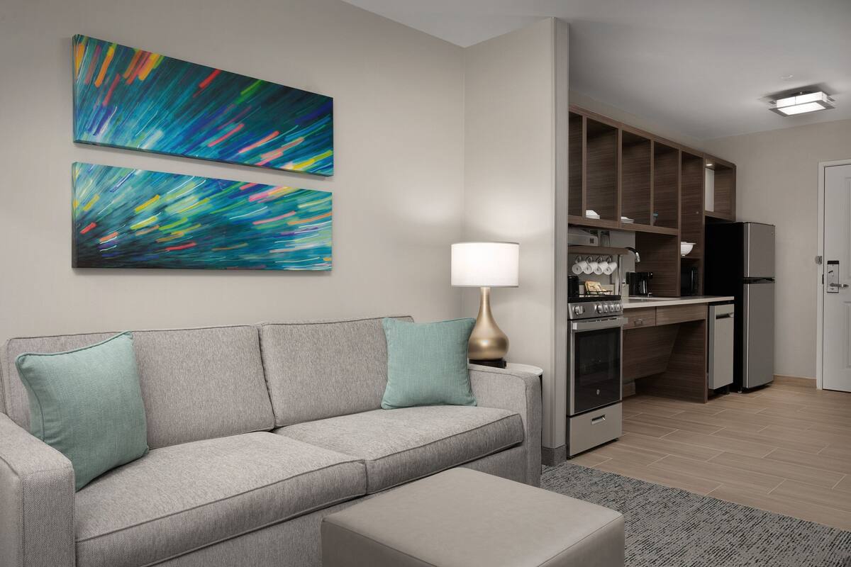 A modern living room with a grey sofa, a small table, and abstract art on the wall.