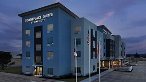 A modern hotel with a blue facade, named Towneplace Suites by Marriott, featuring a parking lot with handicapped spaces and a flagpole with the American flag. - TownePlace Suites by Marriott Abilene Southwest (Abilene)