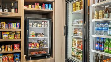 Máquina expendedora llena de aperitivos y bebidas, como papas fritas, barras de chocolate y bebidas embotelladas.