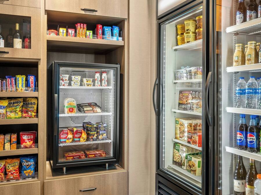 Máquina expendedora llena de aperitivos y bebidas, como papas fritas, barras de chocolate y bebidas embotelladas.