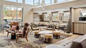 A spacious, well-lit lounge area with multiple seating options, including sofas and chairs, arranged around a central coffee table. Large windows provide ample natural light and views of the outdoors. - Residence Inn by Marriott Homewood Mountain Brook (Birmingham)