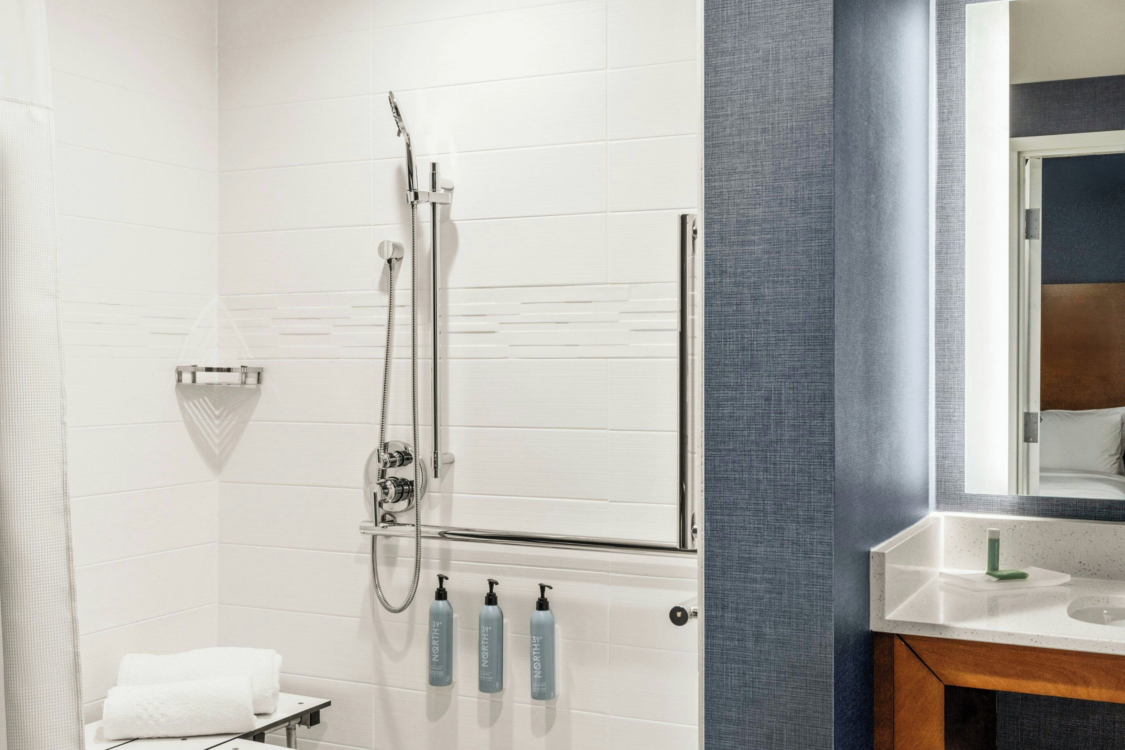 A modern bathroom with a shower, a vanity with a mirror, and toiletries.