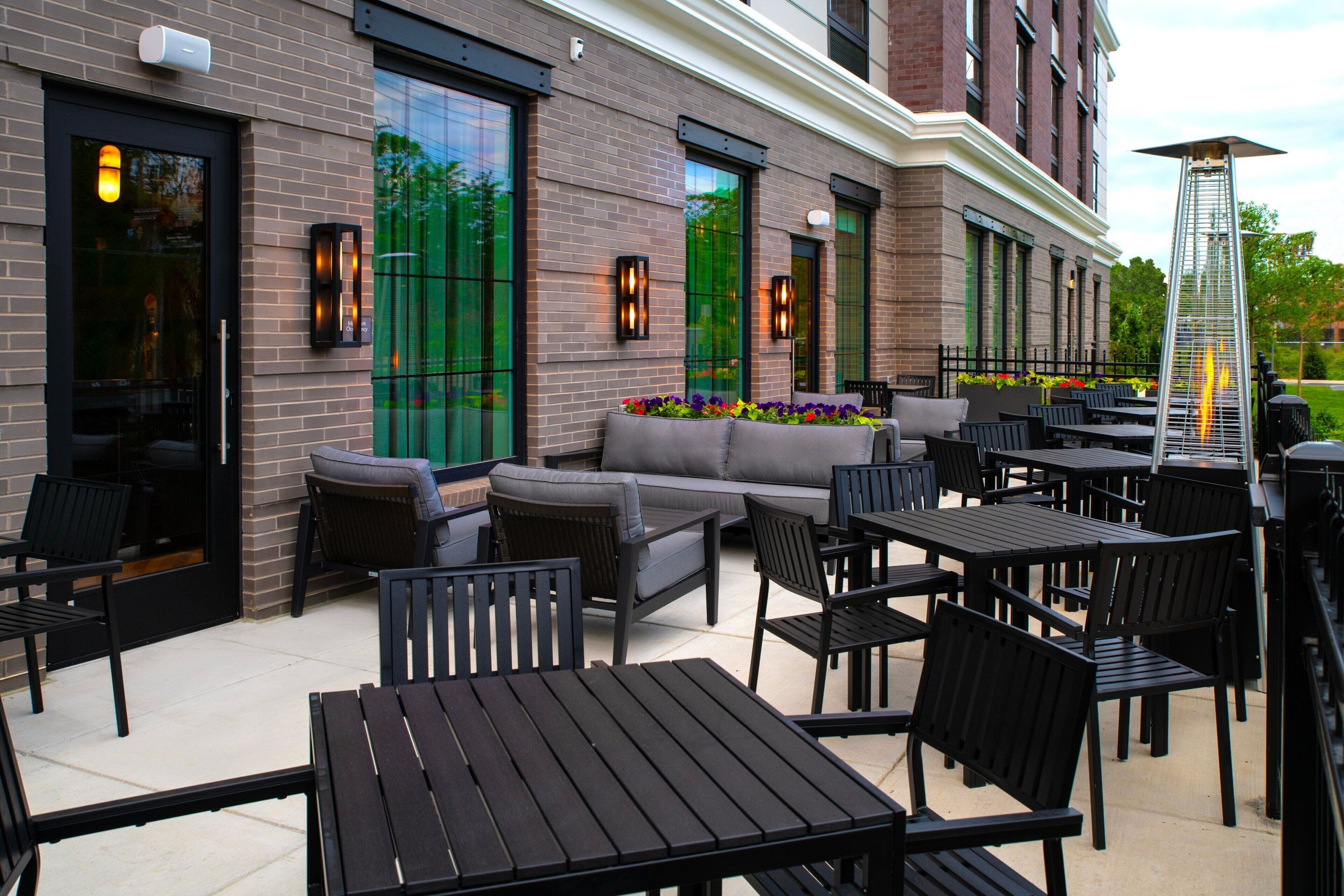 An outdoor seating area with tables and chairs, a sofa, and a fire feature.