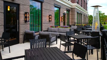 An outdoor seating area with tables and chairs, a sofa, and a fire feature.