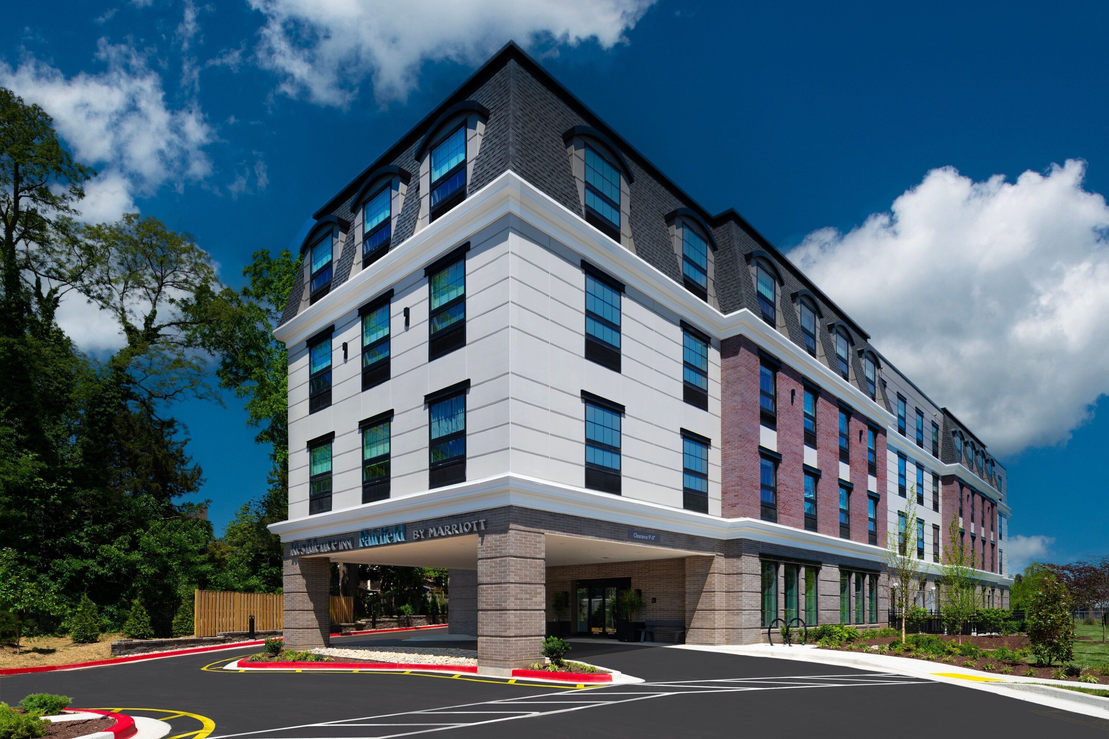 A modern hotel with a flat roof, large windows, and a covered entrance.