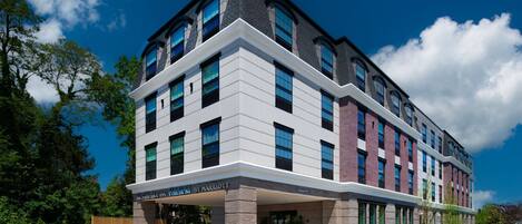 A modern hotel with a flat roof, large windows, and a covered entrance.