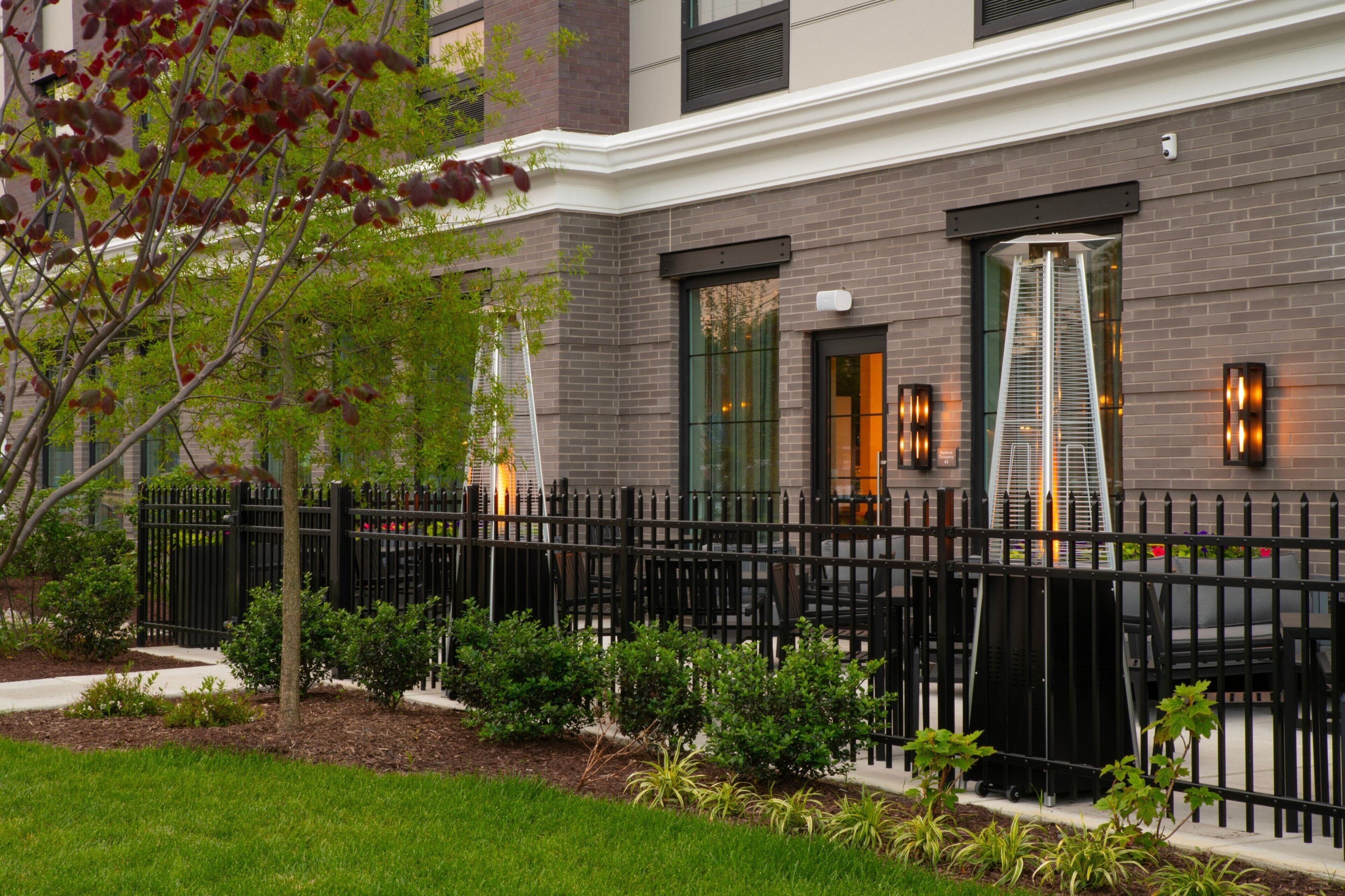 A modern building with a brick facade, large windows, and a black metal fence.