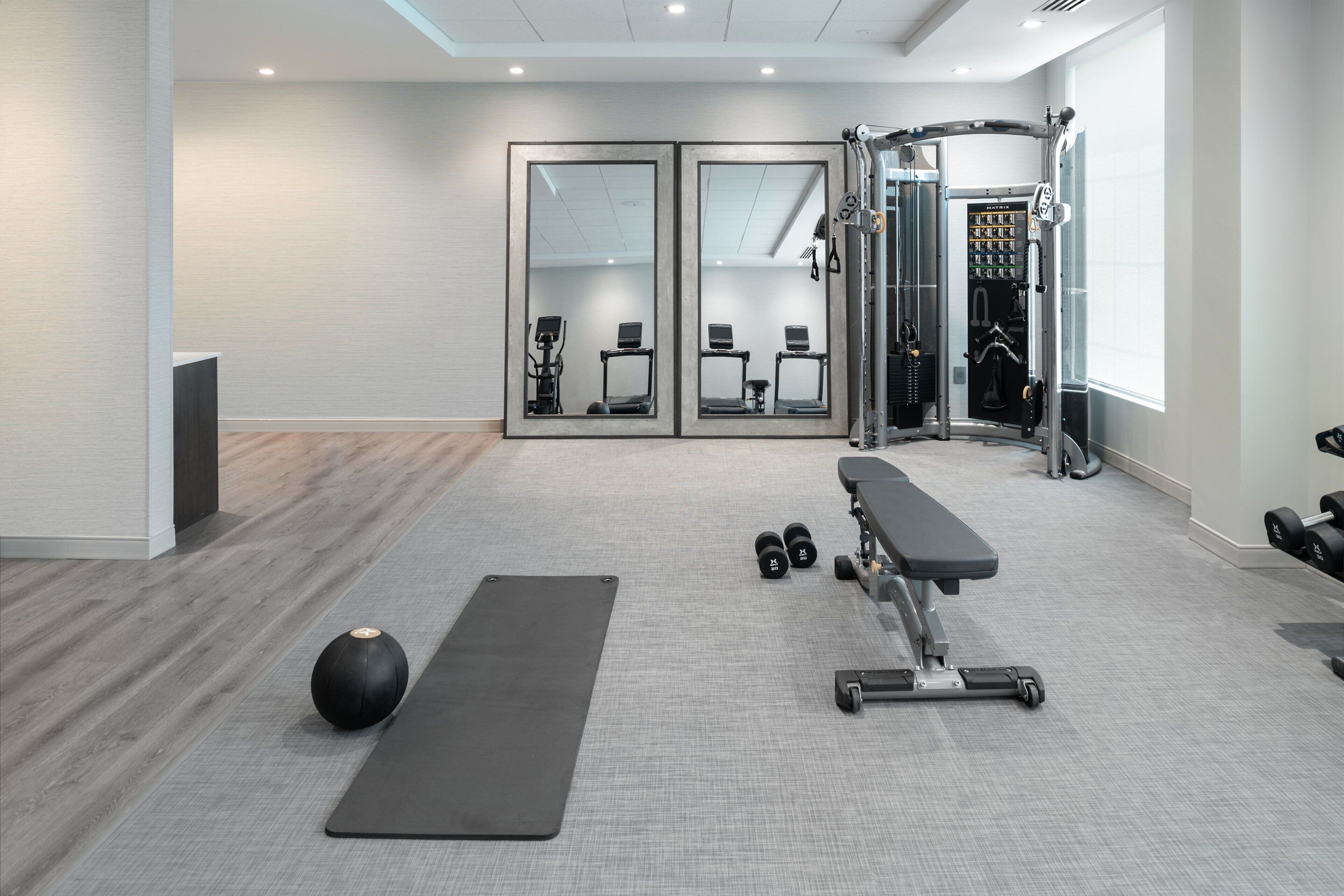 A modern gym with a bench, weights, and a mirror.