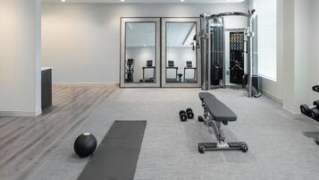 A modern gym with a bench, weights, and a mirror.