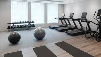 Une salle de sport équipée de tapis de course, de ballons d’exercice et d’haltères.