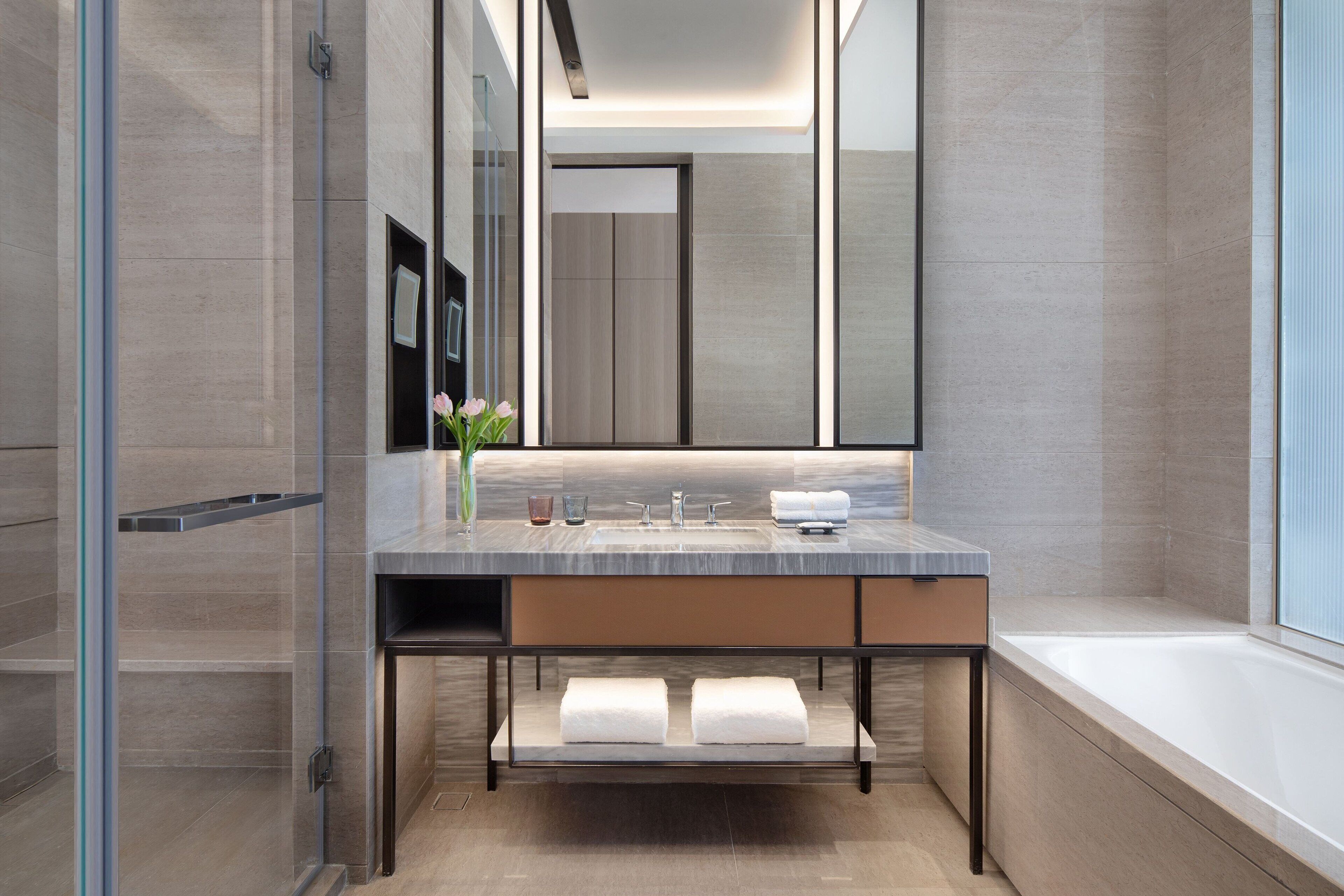 A modern bathroom with a large mirror, a sink, and a bathtub.