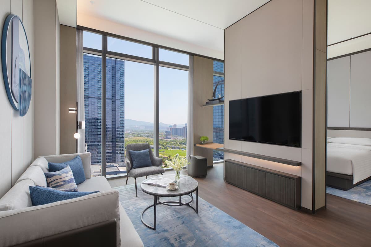 A modern living room with a large TV, comfortable seating, and a view of a cityscape.