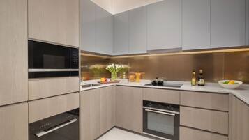 A modern kitchen with built-in appliances, a countertop with a bowl of fruit, and a vase of flowers.