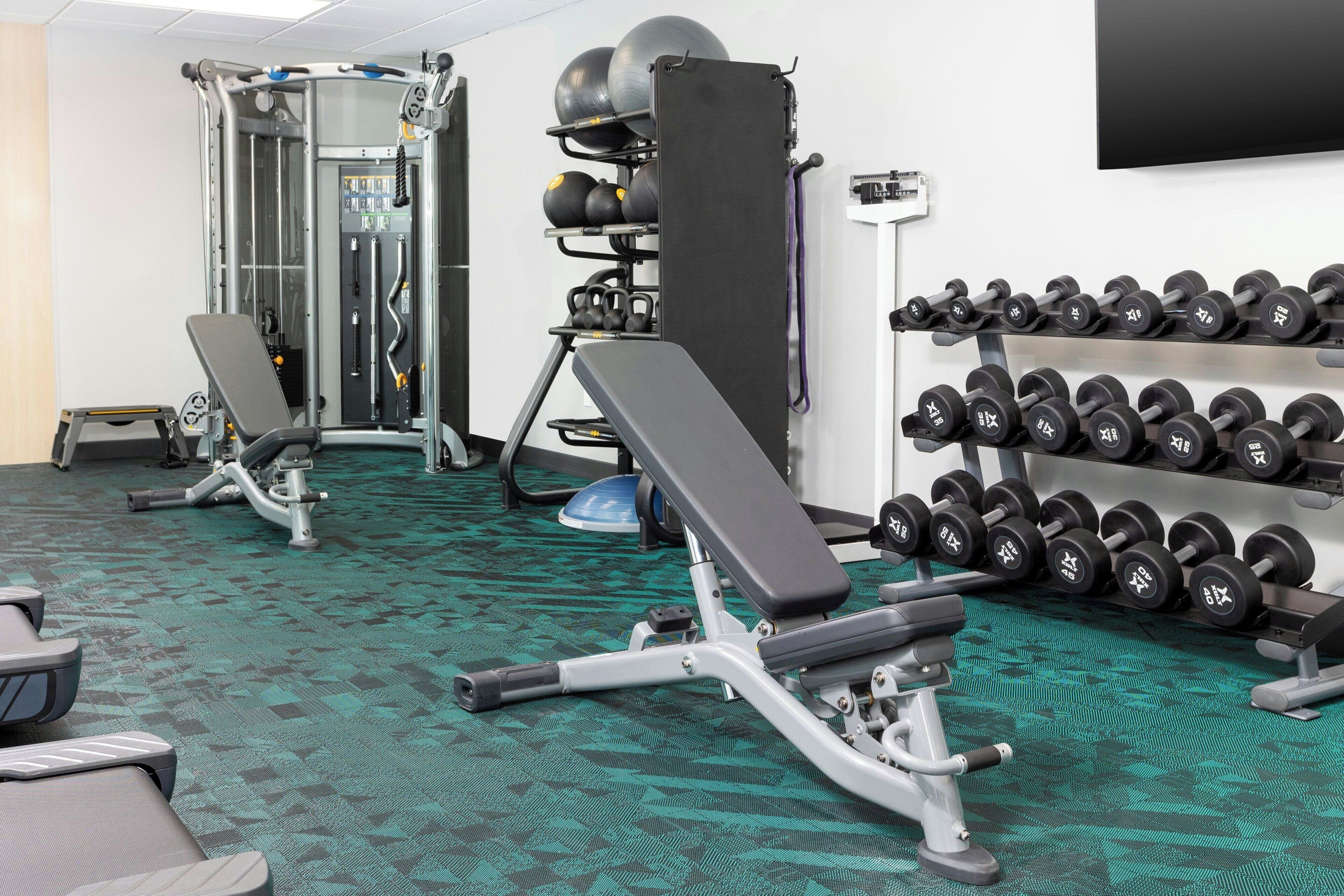 Une salle de sport équipée de matériel de musculation, de bancs et d’un porte-haltères.