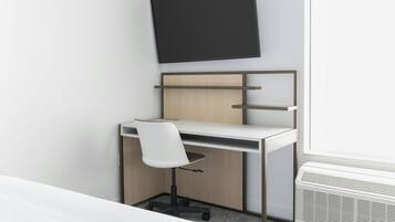 Ein moderner Schreibtisch mit Stuhl, einem an der Wand befestigten Flachbildfernseher und einer integrierten Klimaanlage.