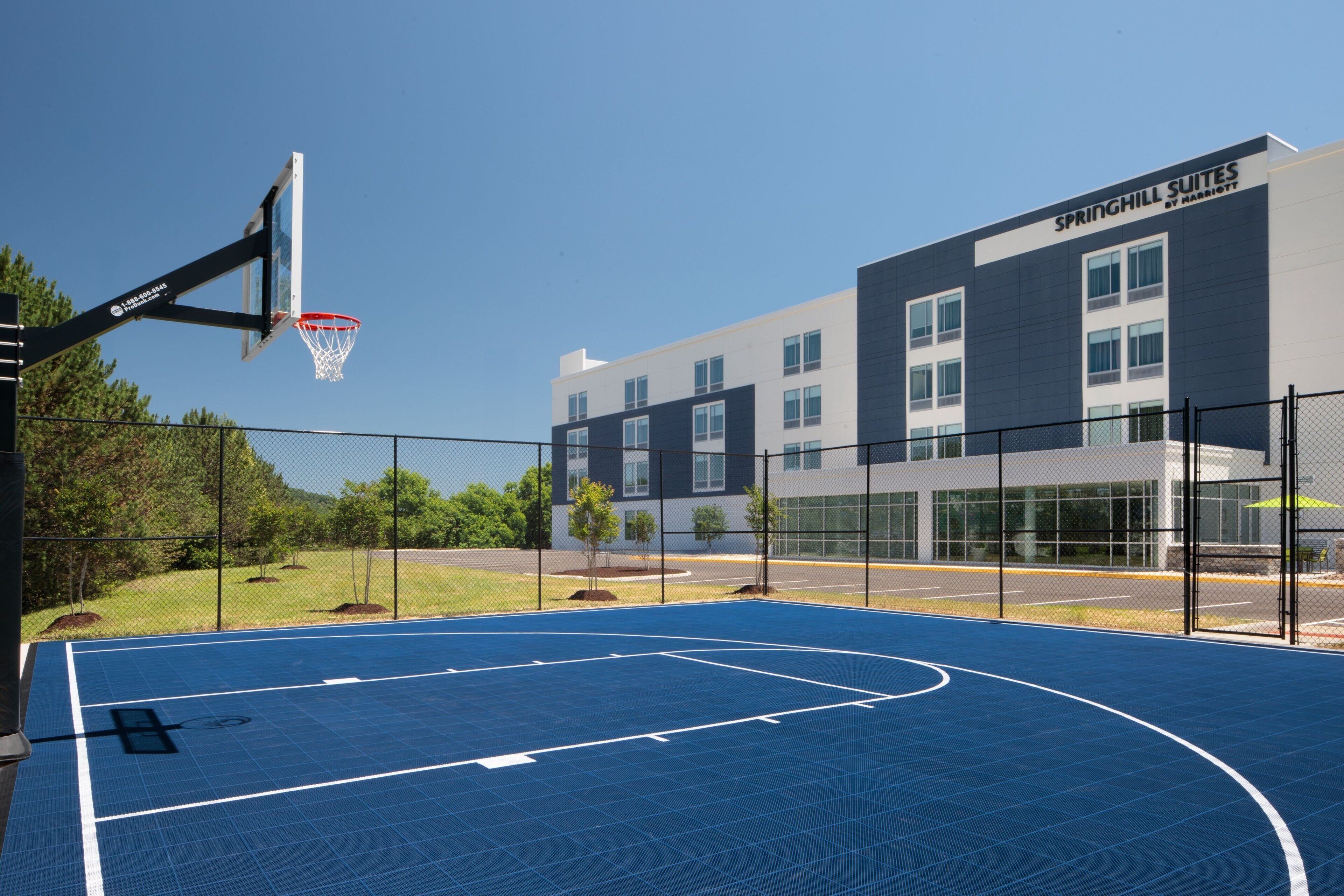 Una cancha de baloncesto al aire libre contigua a un edificio con la leyenda 'Springhill Suites by Marriott'.
