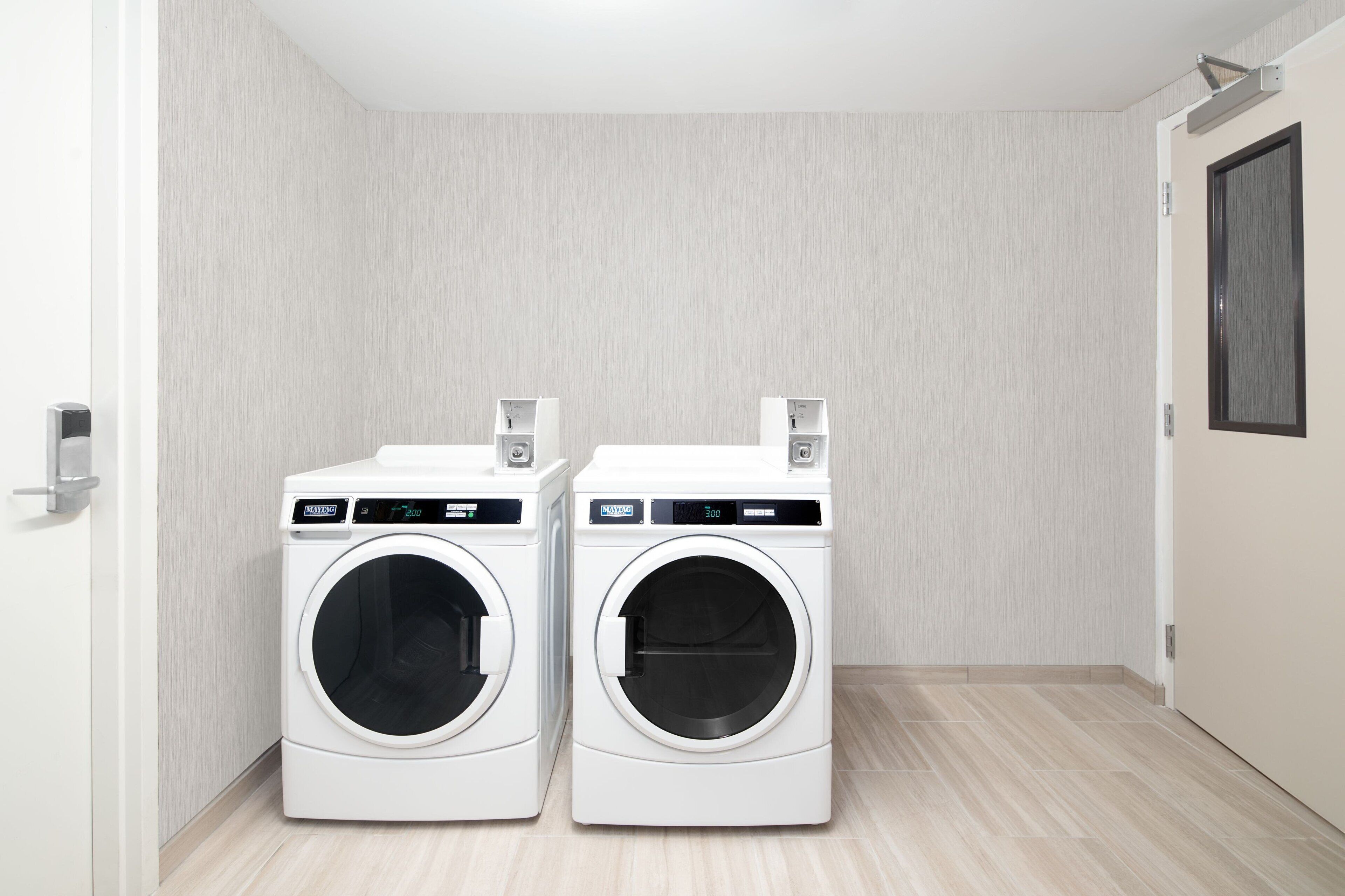 A laundry room with two front-loading washing machines and a door.
