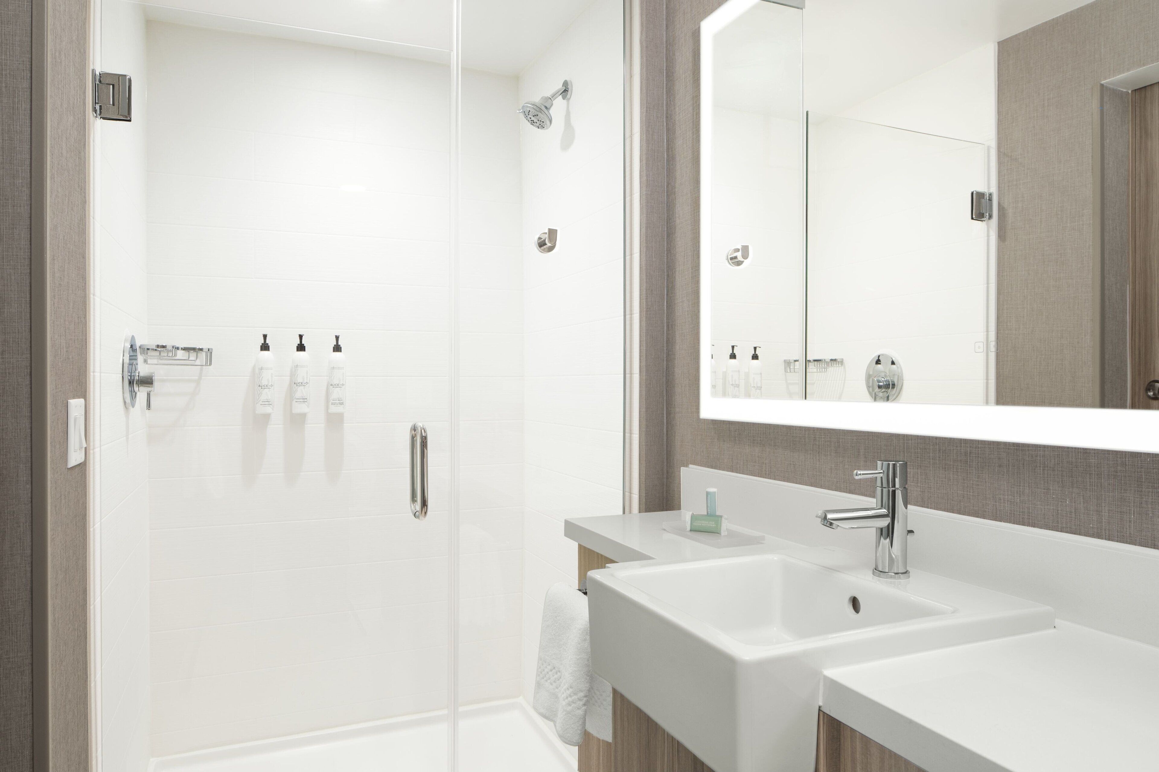 A modern bathroom with a glass-enclosed shower, two sinks, and a large mirror.