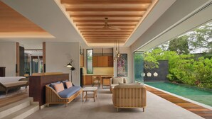 Um interior moderno com teto de madeira, área de cozinha, espaço de estar com sofás e mesa de jantar, e vista para uma piscina e vegetação.