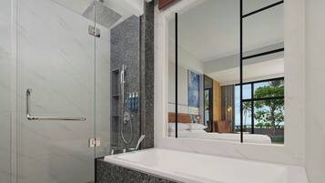 Ein modernes Badezimmer mit einer ein Glasfach stammenden Dusche, einer großzügigen Badewanne und einem großen Spiegel, der ein Schlafzimmer mit Bett und Blick ins Freie reflektiert.
