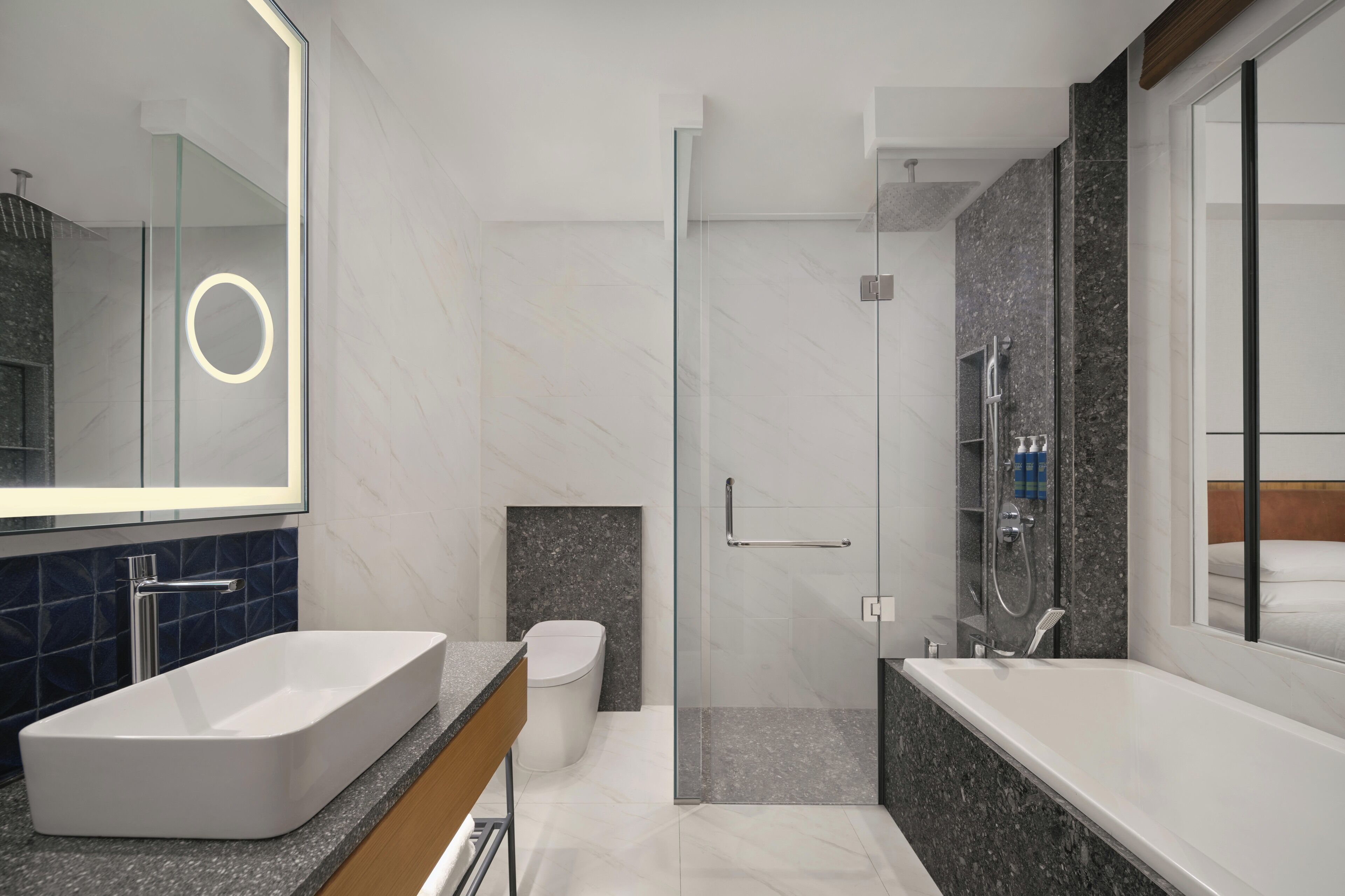 A modern bathroom with a large rectangular sink, a toilet, a glass-enclosed shower, and a large mirror.