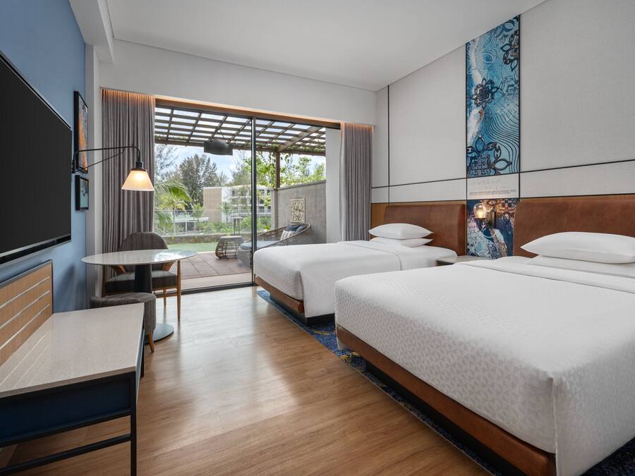 Une chambre d’hôtel avec deux lits, un bureau, une télévision et un balcon avec vue.