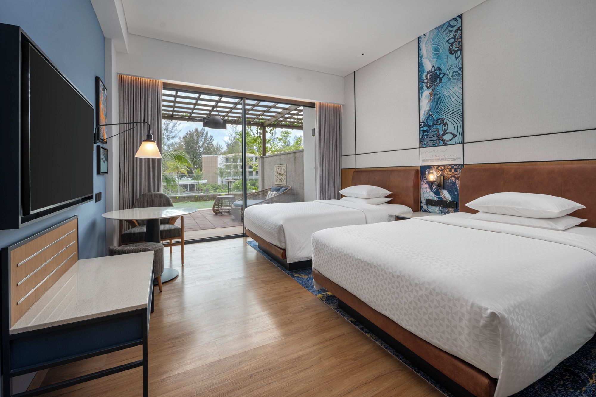 Une chambre d’hôtel avec deux lits, un bureau, une télévision et une vue sur l’extérieur.