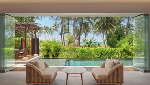 Una habitación moderna con pared de vidrio, piscina y mobiliario de exterior.