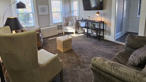 A living room with a sofa, armchair, ottoman, and a TV mounted on the wall. - Steele Brook Manor
Tranquil get away nestled 
in  Litchfield County.  (Watertown)