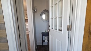 A hallway with a patterned rug, a door with glass panels, and a small table with a fan and a bottle. - Steele Brook Manor
Tranquil get away nestled 
in  Litchfield County.  (Watertown)
