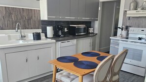 A modern kitchen with white cabinets, a wooden dining table with blue placemats, and a white stove. - Steele Brook Manor
Tranquil get away nestled 
in  Litchfield County.  (Watertown)