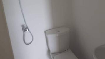 Et lille badeværelse med toilet, bruser og håndvask.