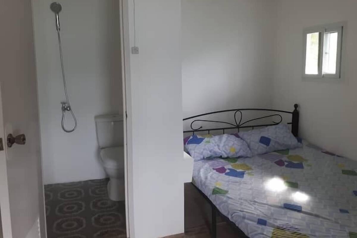 Un dormitorio con cama, ventana y ducha.